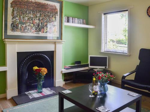 a living room with a fireplace and a table with flowers at Kinnettas Cottage in Strathpeffer