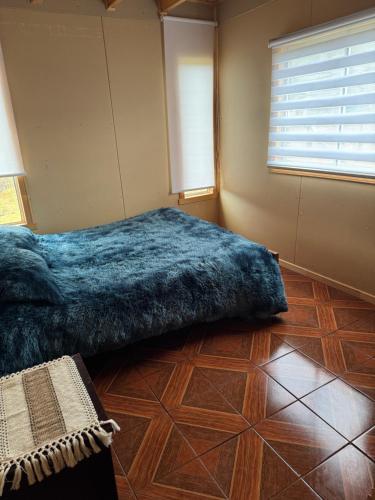 Un dormitorio con una cama con una manta azul. en Cabaña rivera del Captrén, en Curacautín