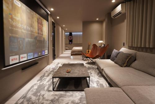a living room with a couch and a large screen at TABISAI HOTEL Luxe 博多 in Fukuoka
