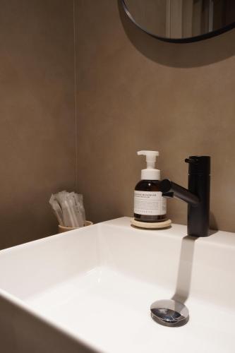 a bathroom counter with a bottle of soap and a faucet at TABISAI HOTEL Luxe 博多 in Fukuoka