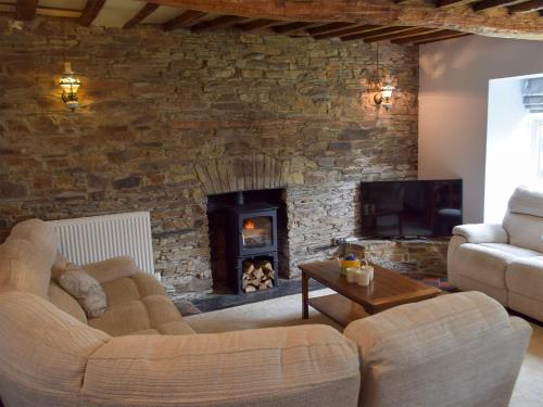 a living room with a stone wall with a fireplace at The Farmhouse - Uk13183 in Cwm-Morgan