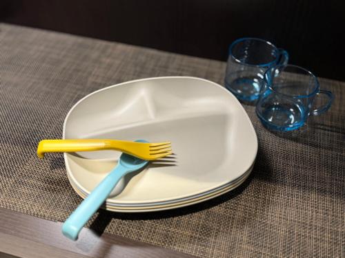 a plate with a fork and two glasses on a table at TABISAI HOTEL Luxe 博多 in Fukuoka