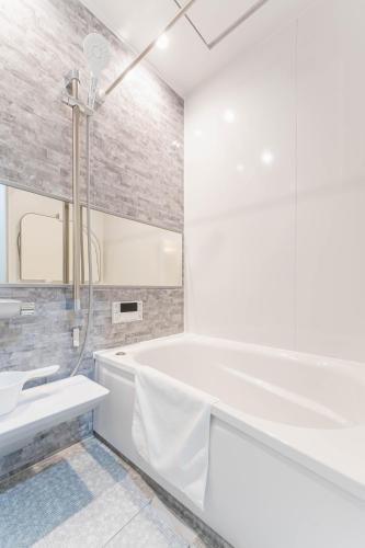 a white bathroom with a tub and a sink at SEIMU Kohama in Osaka