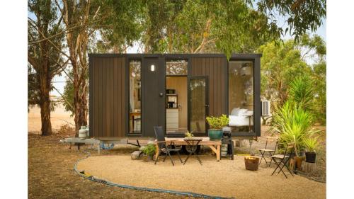 a tiny house in a garden with a table and chairs at Bush Serenity by the Sea by Tiny Away in Bolwarra