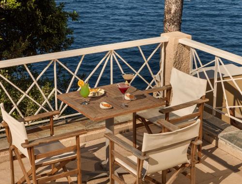 a wooden table and chairs on a balcony overlooking the water at Cape Kanapitsa Hotel & Suites in Kanapitsa