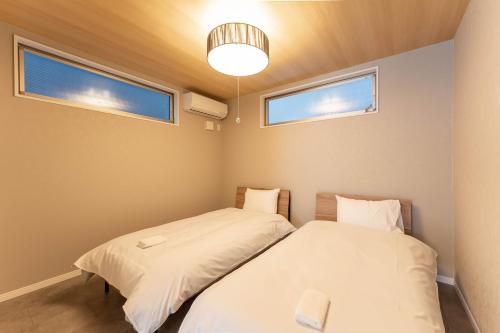 two beds in a room with two windows at SEIMU Kohama in Osaka