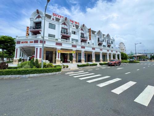 a large white building with a car parked in the street at Hotel 168 Rạch Giá in Rach Gia
