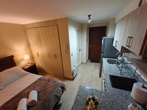 a bedroom with a bed and a kitchen with a sink at Depto centro de chillan con estacionamiento in Chillán