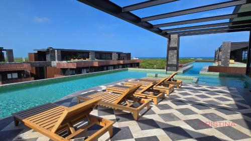 a group of chairs sitting next to a swimming pool at Apartment with Private Jacuzzi, Rooftop Pools & Free beach club in Tulum