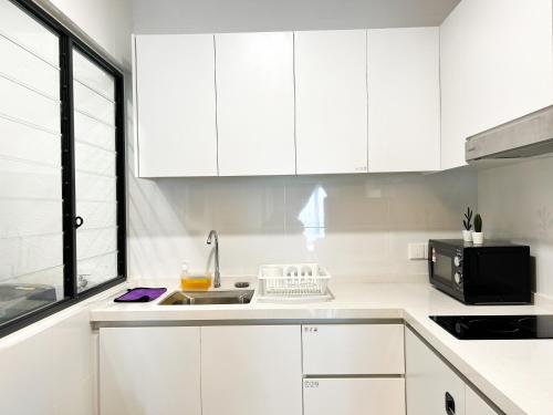a white kitchen with white cabinets and a sink at Tulip Residences by Manhattan Group in Shah Alam
