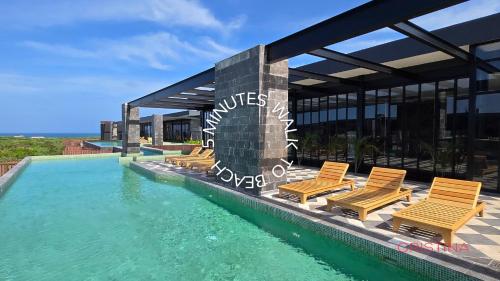 a swimming pool with chairs next to a building at Apartment with Private Jacuzzi, Rooftop Pools & Free beach club in Tulum