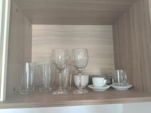 a shelf with wine glasses and bowls on it at Flat temporada in Campos dos Goytacazes