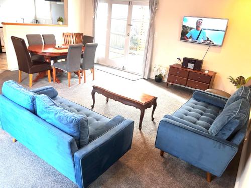 a living room with two blue couches and a table at 298 Home in Christchurch