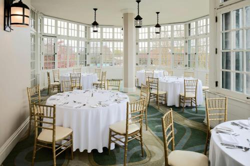 a room with white tables and chairs and windows at The Algonquin Resort St. Andrews by-the-Sea, Autograph Collection in Saint Andrews
