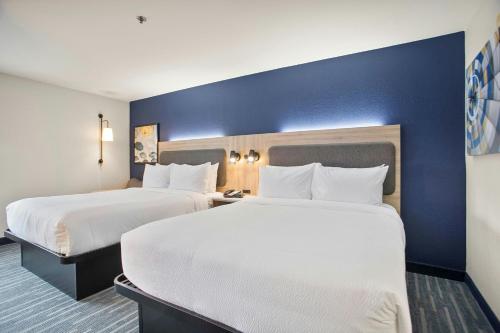 two beds in a hotel room with blue walls at City Express by Marriott Duluth in Duluth