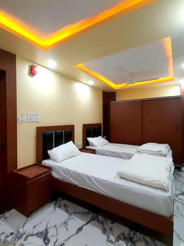 two beds in a room with lights on the ceiling at Hotel The Prince Palace Near Mahabodhi Temple - Wifi and Parking Facilities in Bodh Gaya