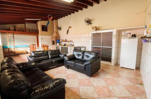 a living room with leather couches and a kitchen at Casa Perequê Açu 500 meters from the beach in Ubatuba