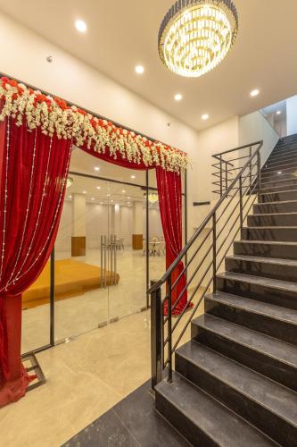 a staircase with red curtains and a chandelier at Limewood Signature - Golf Course Extension Road in Gurgaon