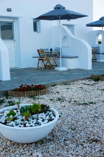 a patio with an umbrella and a bowl of plants at Casa Nostra Mykonos Boutique Rooms & Studios in Glastros