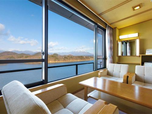 a living room with a table and chairs and a large window at Hotel Shion in Morioka