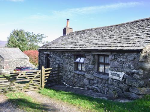 an old stone house with a wooden fence in front of it at Birkerthwaire Stable-W41477 in Eskdale