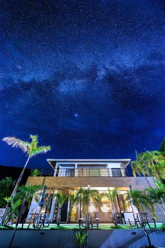 a house under a starry sky with palm trees at amami 星空テラス in Akaoki