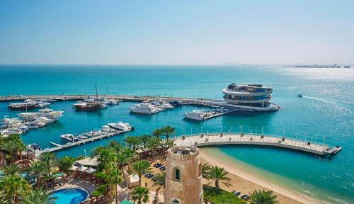 a marina with boats in the water and a clock tower at Four Seasons Hotel Doha in Doha