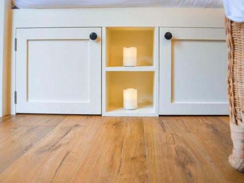 a white cabinet with two candles in it at Helen's Shepherds Hut in Enford
