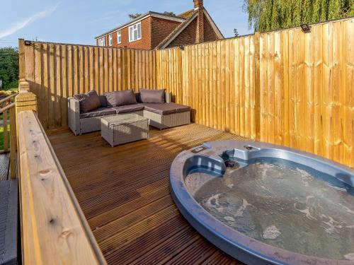 a hot tub on a wooden deck with a couch at Lilac Studio in Wheldrake