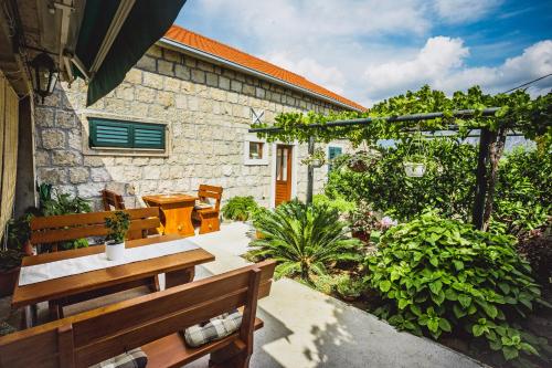 un patio avec des bancs et des plantes et un bâtiment dans l'établissement Kuća Cvjetković, à Gruda