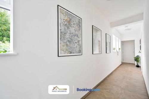 a hallway with paintings on a white wall at 1 Bedroom Apartments By Ramzy Residences Short Lets & Serviced Accommodation In Kent With Free Wifi in Sevenoaks