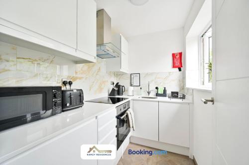 a white kitchen with white cabinets and a microwave at 1 Bedroom Apartments By Ramzy Residences Short Lets & Serviced Accommodation In Kent With Free Wifi in Sevenoaks