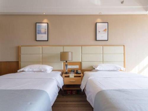 a hotel room with two beds and a table at The Prosperous City Hotel Weifang in Weifang