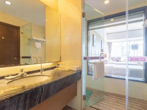 a bathroom with a sink and a large mirror at The Prosperous City Hotel Weifang in Weifang