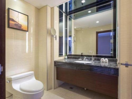 a bathroom with a toilet and a sink with a mirror at The Prosperous City Hotel Weifang in Weifang
