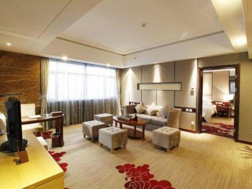 a living room with a couch and a tv in a room at The Prosperous City Hotel Weifang in Weifang