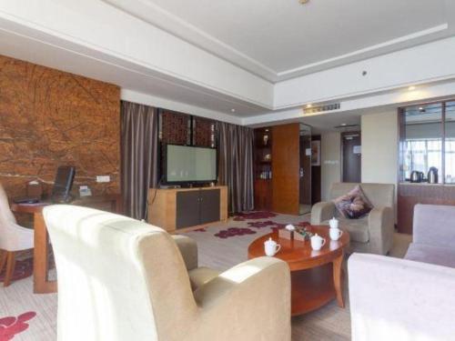 a living room with a couch and a tv at The Prosperous City Hotel Weifang in Weifang