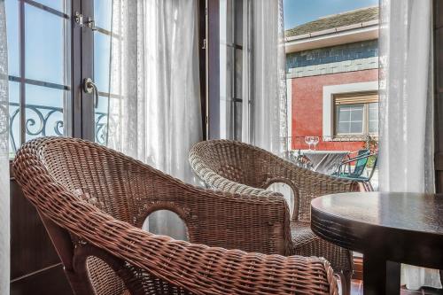 a balcony with two wicker chairs and a table at Hotel Rural Suquin in Navia