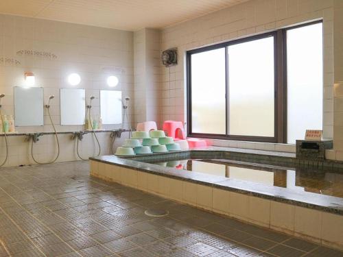 a bathroom with a swimming pool with pink and green chairs at Hotel New Otsuka in Shirako