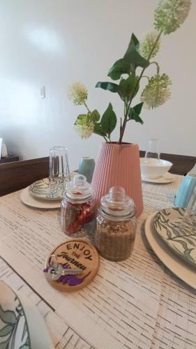 a table with plates and a vase with a plant at 1-Bedroom Casa Sophia Tower in Butuan