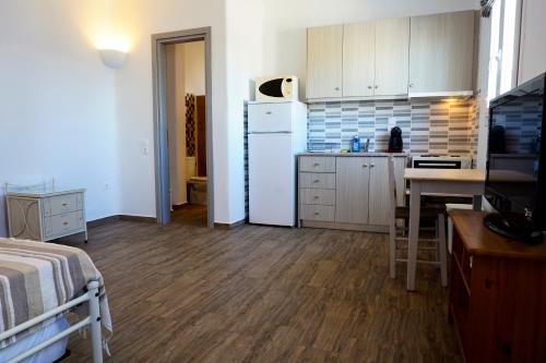 a kitchen with a white refrigerator and a table at Casa Nostra Mykonos Boutique Rooms & Studios in Glastros