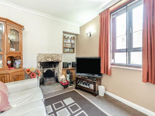 a living room with a fireplace and a television at River Cottage in Two Dales