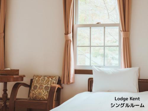 a bedroom with a bed and a chair and a window at Lodge Kent & Cottage Kent in Hokuto