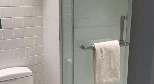 a glass shower door in a bathroom with a toilet at Magnotel Harbin Songbei Wanda Wenlvcheng in Harbin