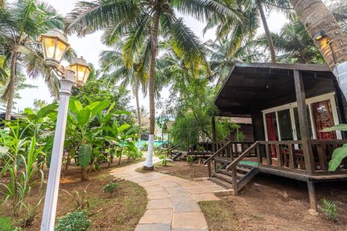 a resort with a porch and a street light and palm trees at The Exotica Agonda in Agonda