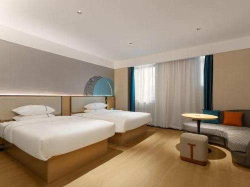 une chambre d'hôtel avec deux lits et une table dans l'établissement City Comfort Inn Huanggang Tuanfeng Passenger, à Luotian