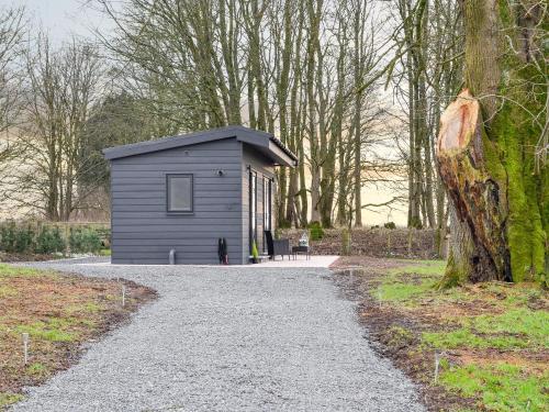 a small grey shed sitting on the side of a road at Lime Tree Lodge in Castle Douglas