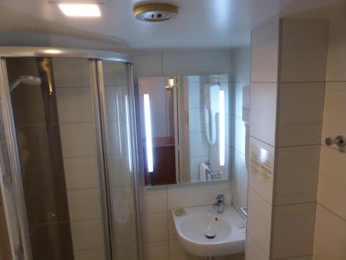 a bathroom with a sink and a shower with a mirror at Hotel & Restaurant Heliotel in Montferrier-sur-Lez