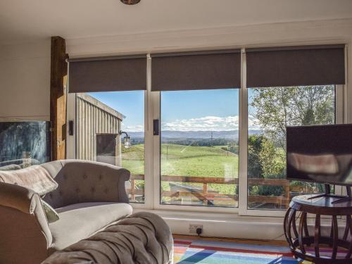 a living room with a couch and a large window at Daisybank Cottage in Crieff