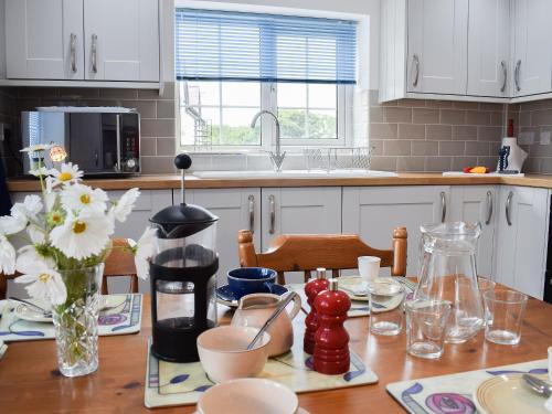 a kitchen with white cabinets and a wooden table at Glasfor in Llanon